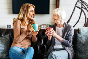 Smiling,Mature,Mother,And,Adult,Daughter,On,Sofa,In,Living